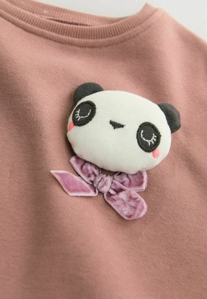Lyserød stof t-shirt med en blød panda applikation med sorte ører og broderede detaljer, prydet med en struktureret lilla sløjfe.