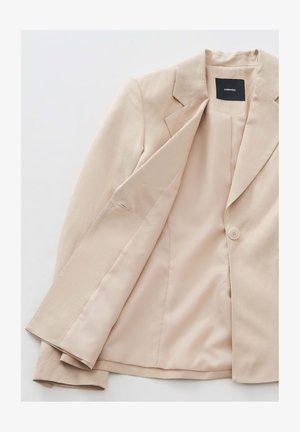 Beiger Blazer aus glattem Stoff. Er verfügt über einen Reverskragen, eine einzelne Knopfverschluss und ein satin Innenfutter.