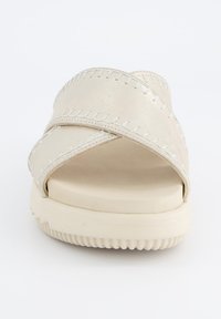 Beige kruisriem sandaal met gestikte accenten, een gladde bovenlaag en een dikke, gestructureerde rubberen zool. Vlak ontwerp voor comfort.