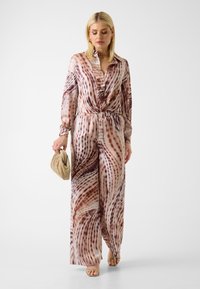 Langer, seidiger Overall mit einem wirbelnden braunen und beigen Muster, mit einem Kragen, Knopfverschluss und elastischem Taillenbund.