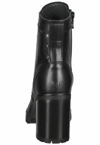 Bottine noire avec un talon bloc haut, fabriquée en cuir lisse. Présente une fermeture éclair sur le côté et des clous en métal près du haut, doublure texturée.