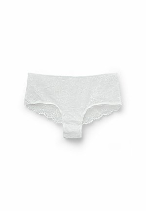 Culotte hipster en dentelle blanche avec un motif floral, des bords festonnés et une ceinture lisse. Texture douce avec une couverture minimale.