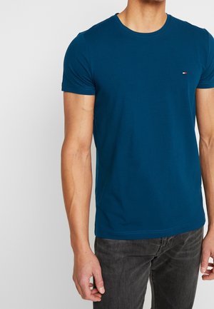 Niebieska bawełniana koszulka z okrągłym dekoltem, krótkimi rękawami i małym logo na piersi. Gładka struktura, dopasowany krój.