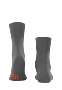 Graue Socken mit geripptem Saum und flachem Strickkörper. Mit orangefarbigem Text an der Seite. Weiche Textur und knöchelhohes Design.