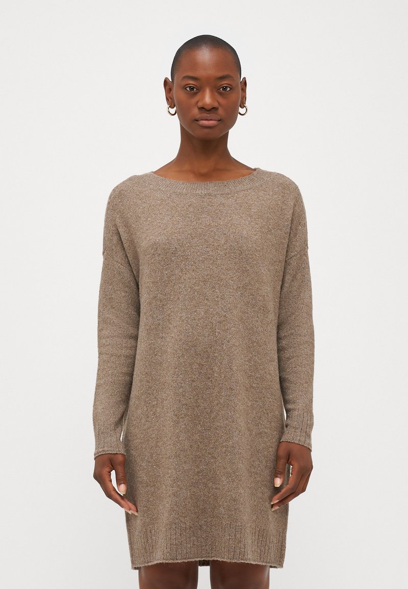 Vestido de malha castanho, com mangas longas, decote barco e bainha canelada. Textura suave e caimento descontraído, atingindo o comprimento até a metade da coxa.