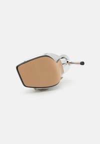Bruine leren schoen met een chroomaccent, vierkante neusvorm en een gestructureerd oppervlak. De zool is glad met een afgeronde hakdetails.