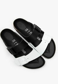 Black and white sandals with adjustable straps and a textured footbed, featuring a smooth upper and durable sole.
