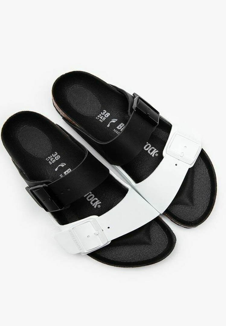 Black and white sandals with adjustable straps and a textured footbed, featuring a smooth upper and durable sole.