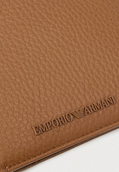Pruun nahast portfoolio tekstuurse pinnaga, mille alumises osas on reljeefne "Emporio Armani" logo. Siledad servad, pehme materjal.