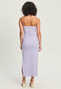 Elegant, lavanda halter haljina s uskim krojem, bočnim prorezom i zatvaranjem na munju na leđima. Glatka tkanina s laganim sjajem.