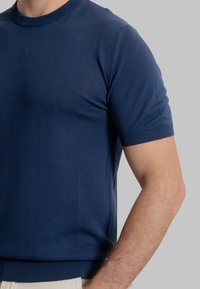 Maglietta a maniche corte in maglia blu navy con scollatura rotonda, dotata di polsini e orlo a coste, evidenziando una texture liscia e un design aderente.