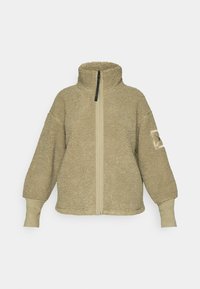 Giacca in pile sherpa beige con colletto alto, zip frontale completa, maniche lunghe e polsini e toppe sui gomiti in similpelle sul braccio sinistro.