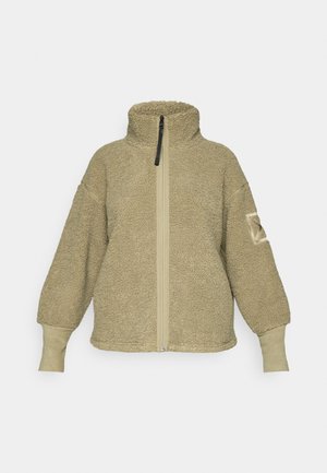 Beige sherpa fleece jack met hoge kraag, volledige rits aan de voorkant, lange mouwen, en suède-achtige manchetten en elleboogpatch op de linkermouw.
