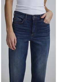 Mörkblå denimjeans med rak passform, med knäppning och dragkedja, framfickor och kontrasterande sytt detaljer.