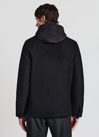 Cappotto nero dalla texture particolare con cappuccio in raso nero, polsini con bottoni e taglio dritto, pensato per una silhouette moderna.