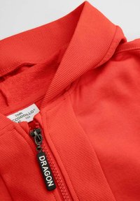 Czerwona kurtka zapinana na zamek z prążkowanym kołnierzem i teksturowanym materiałem. Posiada czarny suwak z etykietą "DRAGON". Metka wskazuje rozmiar 10 lat.