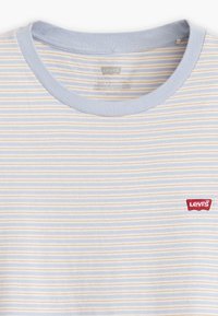 Light blue t-shirt featuring horizontal stripes in pale yellow. Crew neck design with a red Levi's logo tag on the chest. Soft fabric texture.