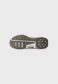 Løbesko sål i sort og grå, med et tekstureret grebmønster, skrå studs til traction og en hvid mellemsål.