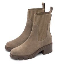 Ett par taupe mocka ankelskor med ribbat stickat elastiskt material på sidorna, dragflikar bak och kraftiga gummisulor med blockklackar.