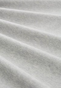 Tissu gris clair avec une surface douce et texturée, présentant de légères rides et une finition lisse, indiquant élasticité et confort.