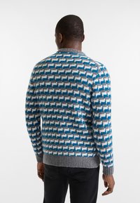 Maglione lavorato a maglia in blu, grigio e crema con un motivo geometrico. Orlo e polsini a coste grigi. Texture morbida, scollatura a girocollo, maniche lunghe.