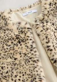 Beige színű műszőrme dzseki fekete leopárdmintával. Puha tapintású és egyszerű, kerek nyakkivágású. A márkajelzés látható a belső részén.