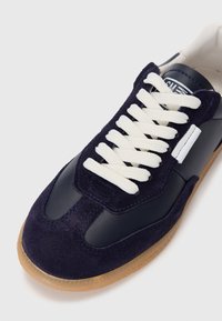 Marineblå semsket og skinn sneakers med hvite lisser, en gummisåle og en blank overflate. Har blå sømmer og et minimalistisk design.