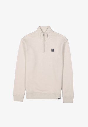 Jersey de color crema hecho de una tela suave; cuenta con un cuello de media cremallera, puños acanalados y un pequeño parche de logo en el pecho.