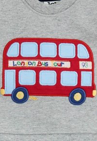 Rød broderet dobbeltdecker bus design på en grå sweatshirt. Har blå vinduer, farverig tekst og gule hjul.