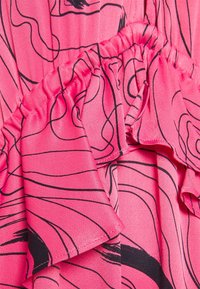 Tissu rose vif avec motifs de lignes abstraites noires et détails froncés.