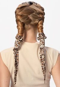 Flettet hår med to leopardmønstrede hårstrikker. Hårstrikkene er detaljerte med brune flekker på en kremfarget bakgrunn. Jevn tekstur observert.