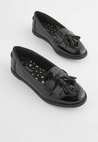 Czarne lakierowane loafersy z detalem w postaci frędzli, o zakrzywionym kształcie i wkładkach w gwiazdki. Gładka tekstura i niska podeszwa.