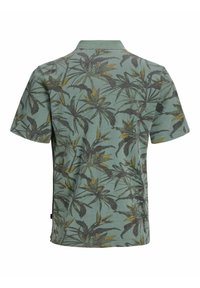Polo vert à manches courtes avec motif de feuilles tropicales vert foncé et jaune, vu de dos.