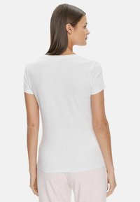 Maglietta a maniche corte bianca con scollatura rotonda e forma aderente, realizzata in cotone liscio senza motivi né decorazioni.