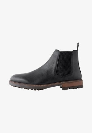 Bottine Chelsea en cuir noir avec panneau latéral élastique texturé, languette au talon, semelle marron et semelle extérieure à crampons robustes.