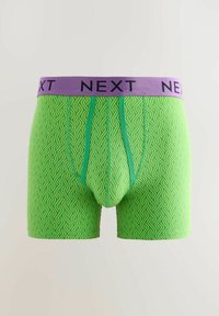 Boxer-briefs verts avec un motif ondulé, dotés d'une ceinture violette unie portant l'inscription "NEXT". Le matériau semble doux avec un design ajusté.