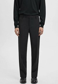 Pantalons noirs ajustés avec un design à plat et deux poches latérales. Fabriqués en tissu lisse, avec une coupe droite et un détail de pli subtil.