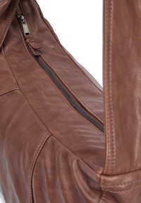 Braune Leder-Schultertasche mit sichtbar Reißverschluss, weicher Textur und runder Form, die über Steppnähte und ein schlankes, strukturiertes Design verfügt.