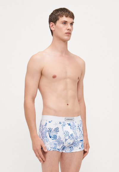 Boxers en coton blanc pour hommes avec un imprimé thématique marin bleu. Ce modèle dispose d'une ceinture élastique blanche avec le logo "VERSACE" sur le devant.