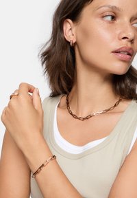 Roséguld smyckesset med en kraftig kedjehalsband, matchande armband och rektangulära hoop örhängen. Slät yta, modern design.