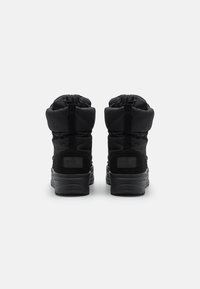 Botas de invierno negras con parte superior acolchada, puño elástico y suelas de goma negra gruesa. Presenta un acabado texturizado y una tira en la parte trasera para ayudar a ponérselas.