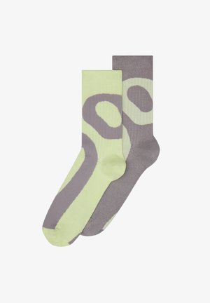 Zielone i szare skarpetki o odważnym abstrakcyjnym wzorze, wykonane z gładkiego materiału, z prążkowanymi sekcjami i kontrastowymi detalami.