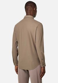 Camisa de manga larga de tela marrón claro con cuello, yugo trasero y puños abotonados; textura suave y corte holgado.