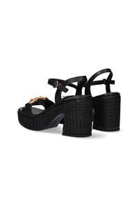 Sandalias de plataforma negras con un tacón tejido texturizado, que cuentan con una correa para el tobillo ajustable y acentos decorativos en la parte delantera.