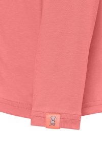 Różowa koszulka z długim rękawem, wykonana z miękkiego materiału. Posiada metkę z logo na mankiecie z małym wzorem oraz delikatne szwy wokół krawędzi.