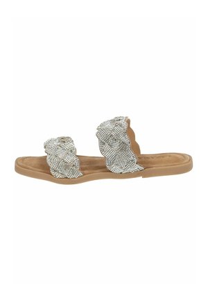 Sandales plates avec une semelle beige et deux lanières en maille argentée. Les lanières présentent un design ondulé et sont ornées de petites embellissements brillants.