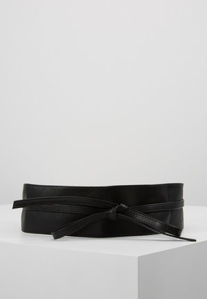 Black leather waist belt with a wraparound design tied in a knot, displayed on a white pedestal against a gray background.