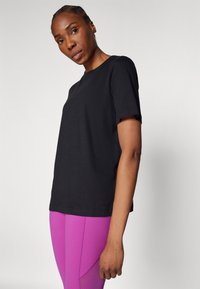 Schwarzes Crewneck-T-Shirt mit kurzen Ärmeln, aus Baumwolle gefertigt. Bietet einen lockeren Schnitt und ein kleines Logodetail am Saum.