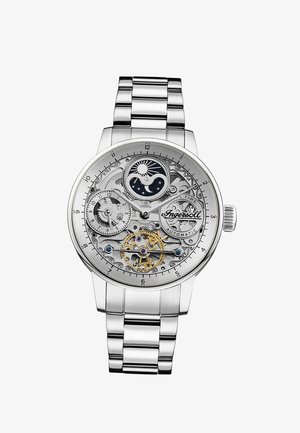 Zilveren automatische horloge met zichtbare tandwielen, wijzerplaat voor maan- en zonnefasen, 24-uurs subwijzerplaat en metalen schakelarmband.