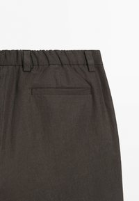 Pantaloni grigio scuro con elastico in vita, passanti per cintura e una singola tasca posteriore a filetto, mostrati su sfondo bianco.